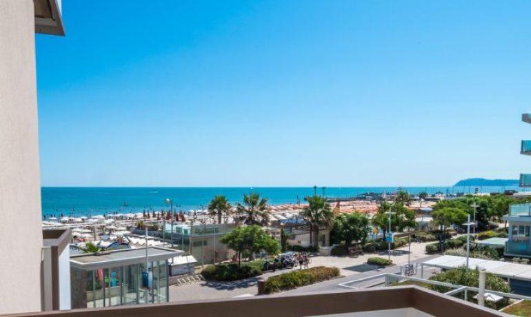 Balcone con vista mare e due sedie bianche.