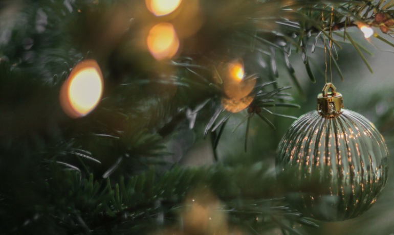 Ornamento natalizio dorato su albero con luci soffuse.