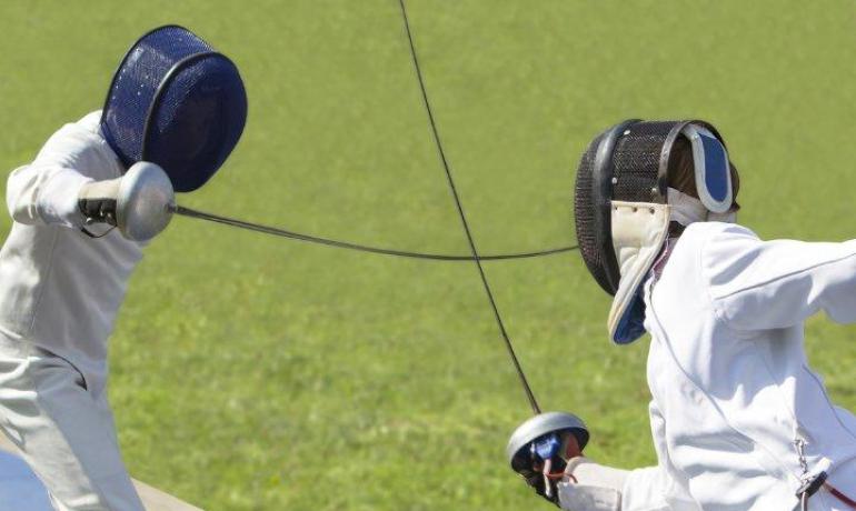 Due schermidori in azione su una pedana all'aperto.