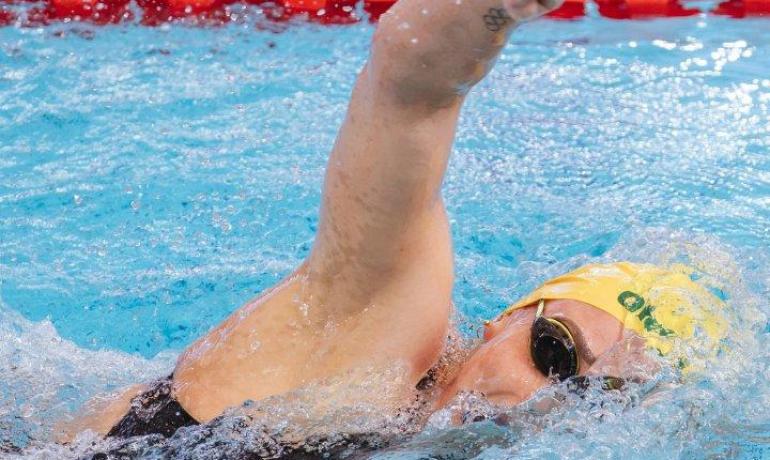 Nuotatore in piscina con cuffia gialla e occhialini.
