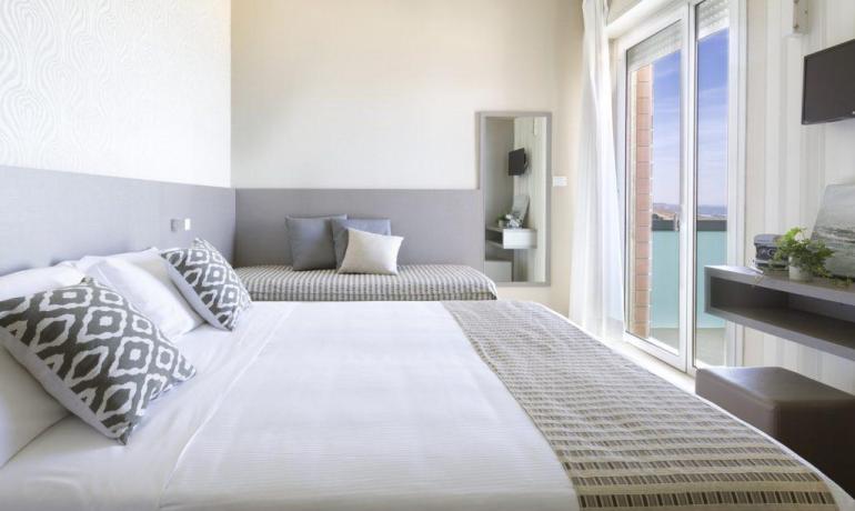 Camera luminosa con letto elegante, vista mare e atmosfera rilassante.