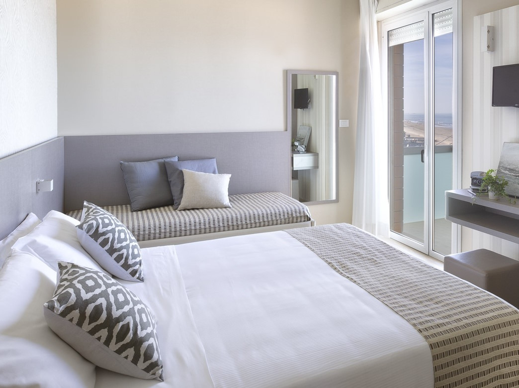 Camera moderna con letto matrimoniale, divano, vista mare e decorazioni eleganti.