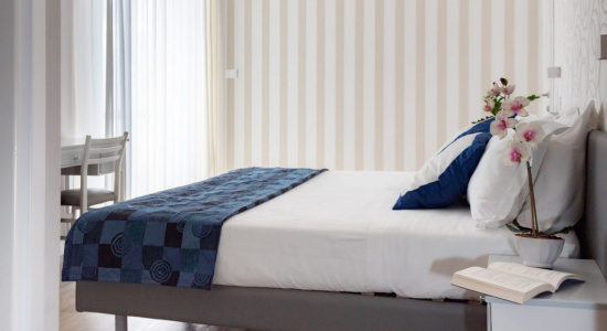 Camera da letto moderna con letto matrimoniale, coperta blu e decorazioni floreali.